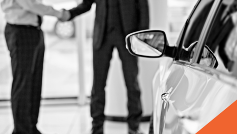 new car in the foreground with two men shaking hands in the background for a car sale | Billyard Insurance Group