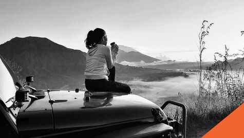 summer road trip | Billyard Insurance Group | Woman watching sunset on car