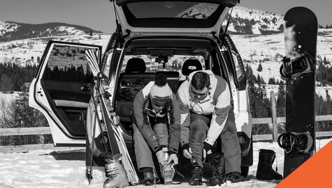 Two people preparing to ski and snowboard on a mountain