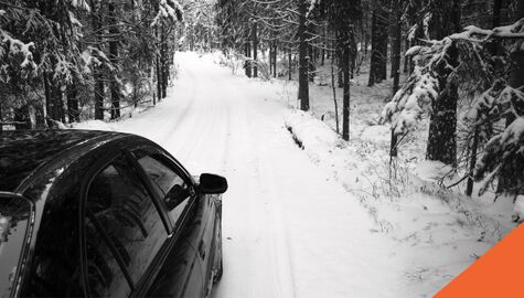car driving on snowy road through forest