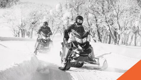 2 snowmobiles riding through snow