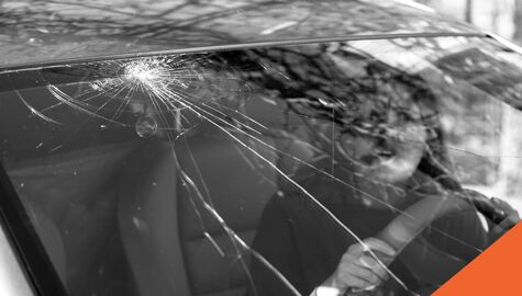 Person in vehicle looking at a crack in their windshield