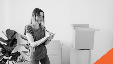 Woman writing on a notepad with moving boxes in the background