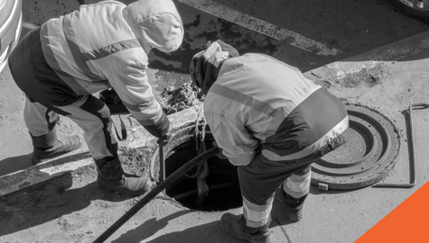 Two workers cleaning a sewer drain